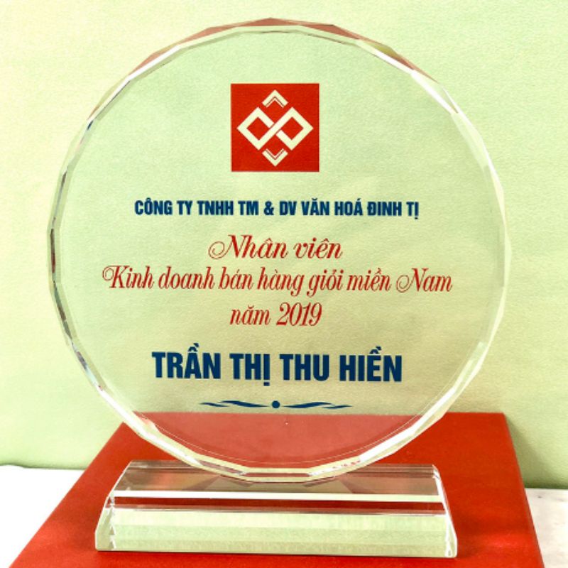 Ảnh nguồn mặt tròn pha lê với logo phía trên, nội dung ghi nhận và tên người nhận bên dưới