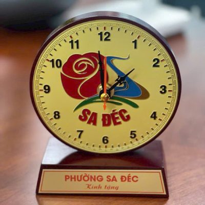 Ảnh nguồn đồng hồ gỗ mặt đồng với nhận diện giữa mặt giờ và lời tặng ở chân đế