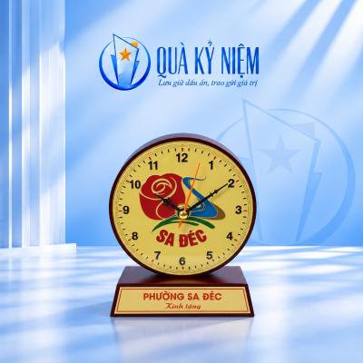 Đồng hồ gỗ mặt đồng màu vàng, khung nâu và bảng lời tặng trên nền Quà Kỷ Niệm